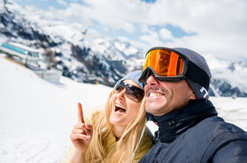 A man wearing ski goggles and a woman wearing sunglasses on the snow